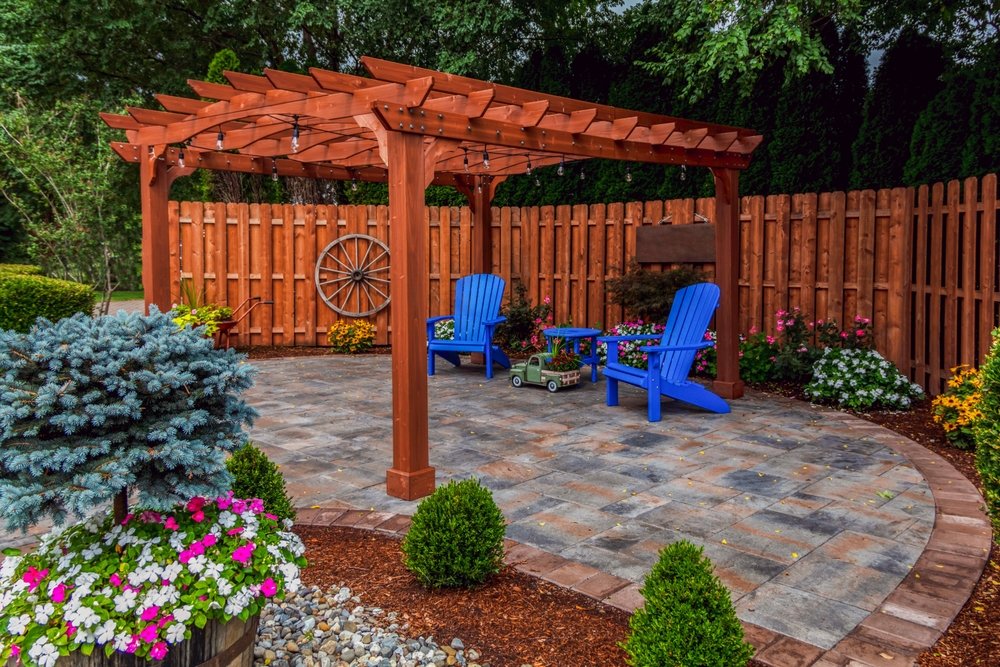 backyard patio with blue chairs and a wooden awning, and flowers