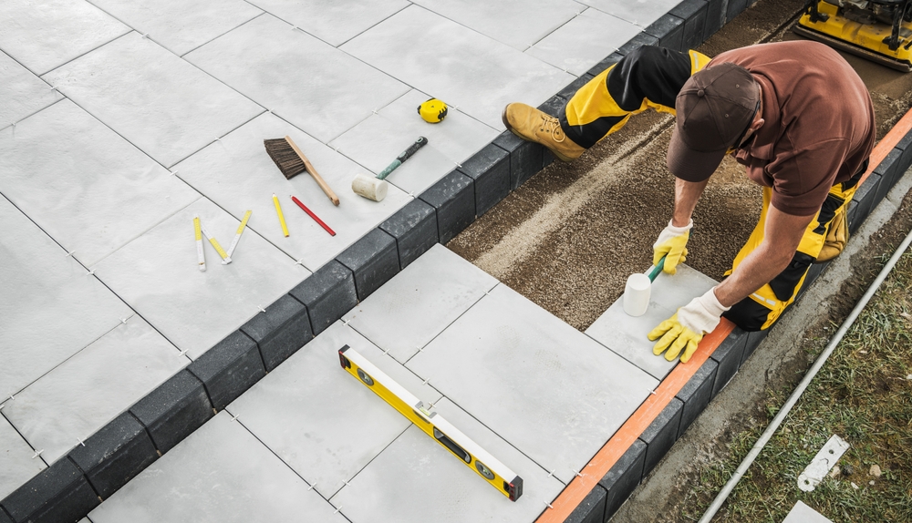 man working on installing cement patio or surface in backyard