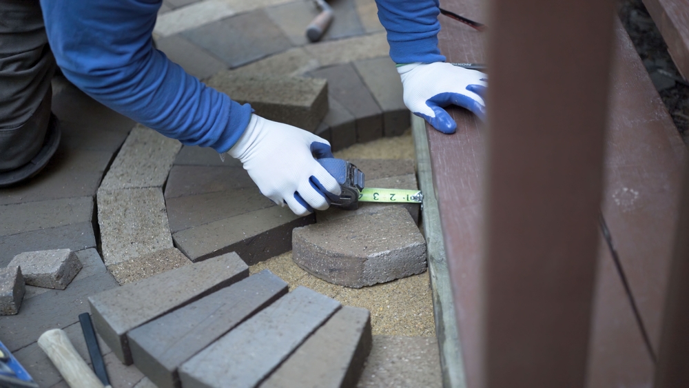 worker measuring hardscape brick installation