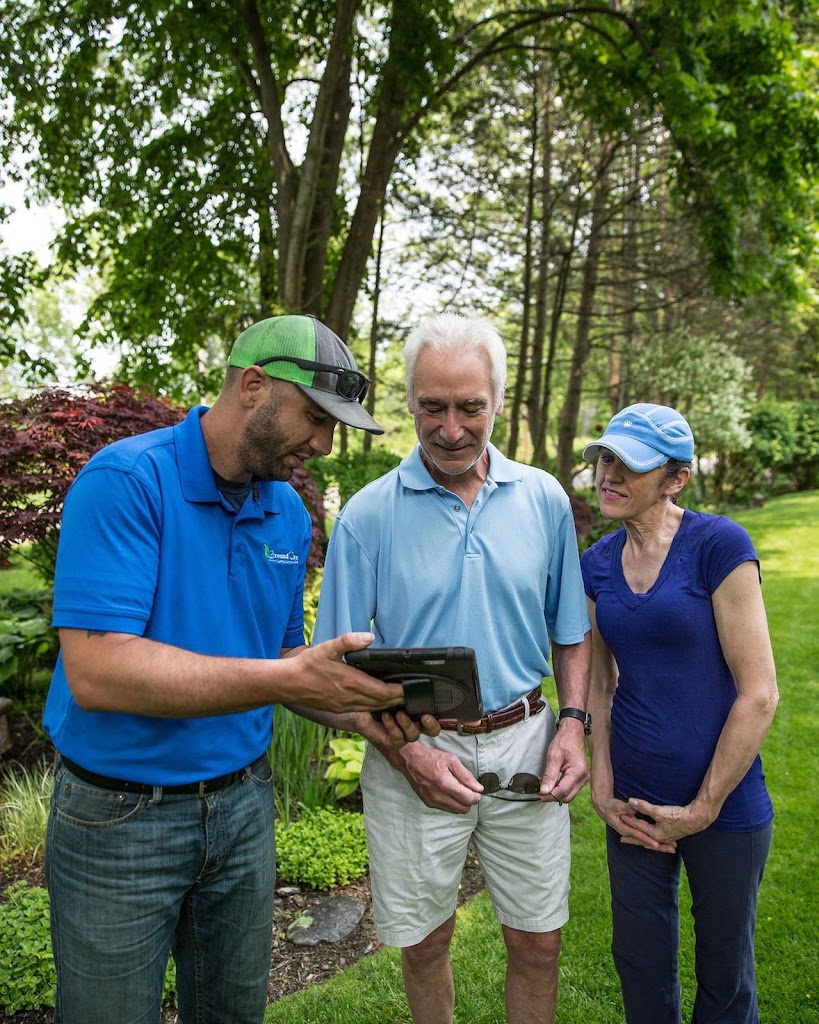 Landscaping expert at Ground at Care Landscaping speaking with customers while using an ipad