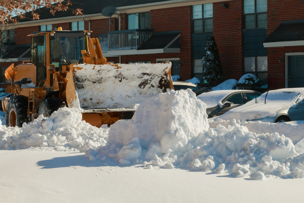 Snow plough truck clearing road after winter snowstorm blizzard for vehicle access