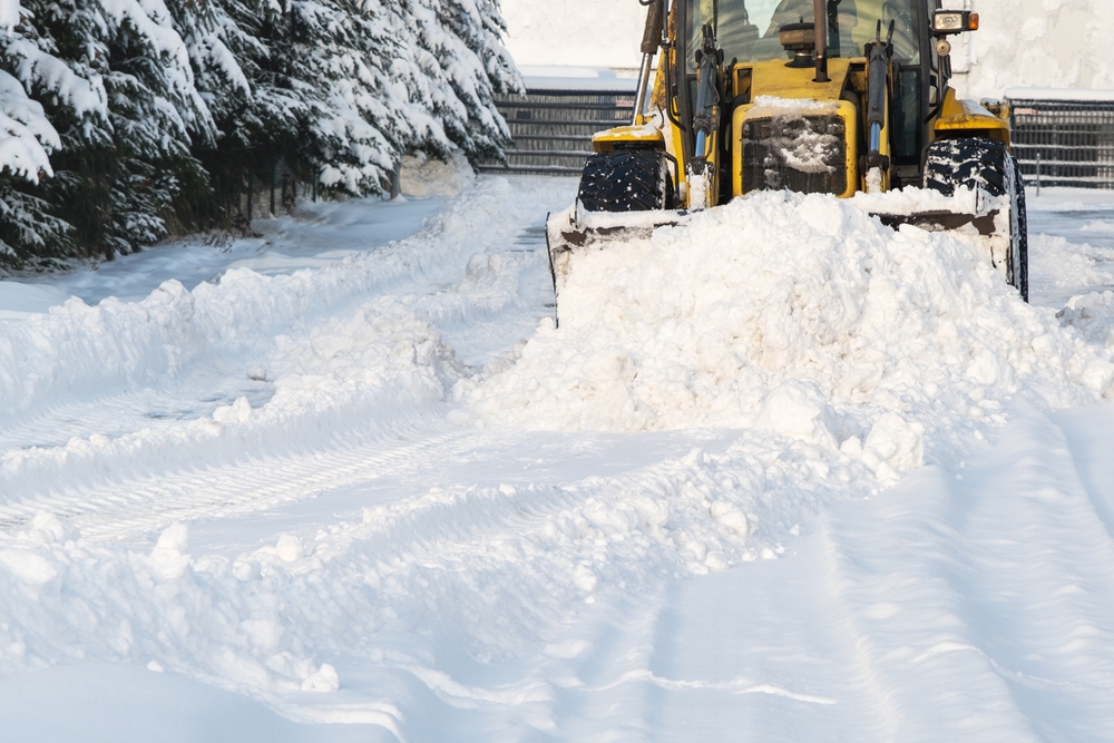 Yellow skid steer removing excess snow from property