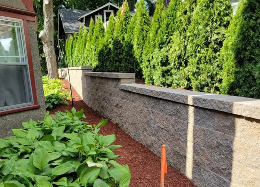 Retaining wall near brown mulch and green trees