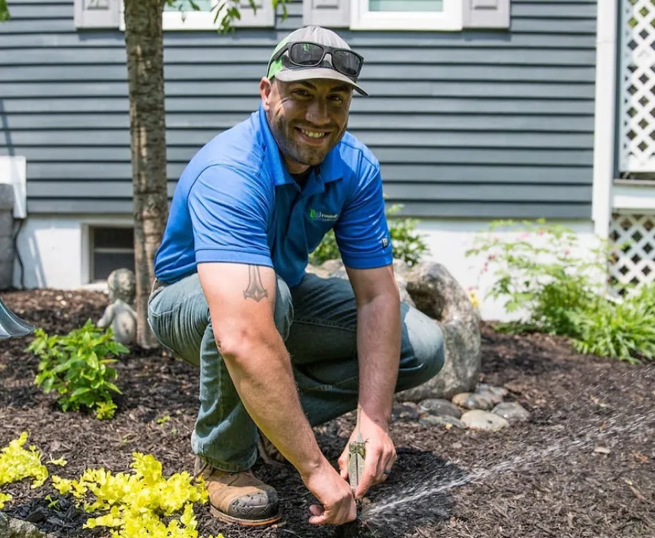 Ground Care Landscaping team member on mulch wearing hat and sunglasses
