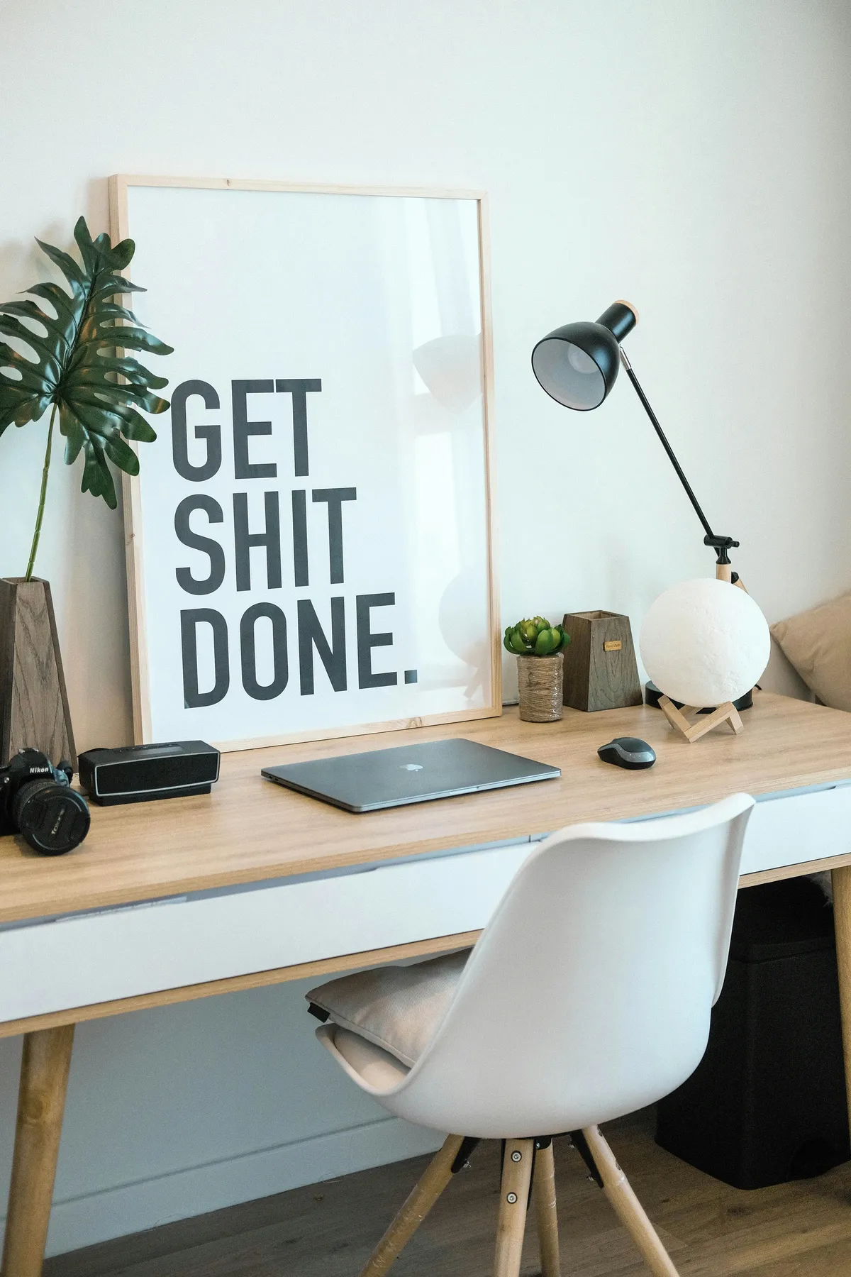 Bright home office desk with a framed motivational poster, a laptop and a desk lamp