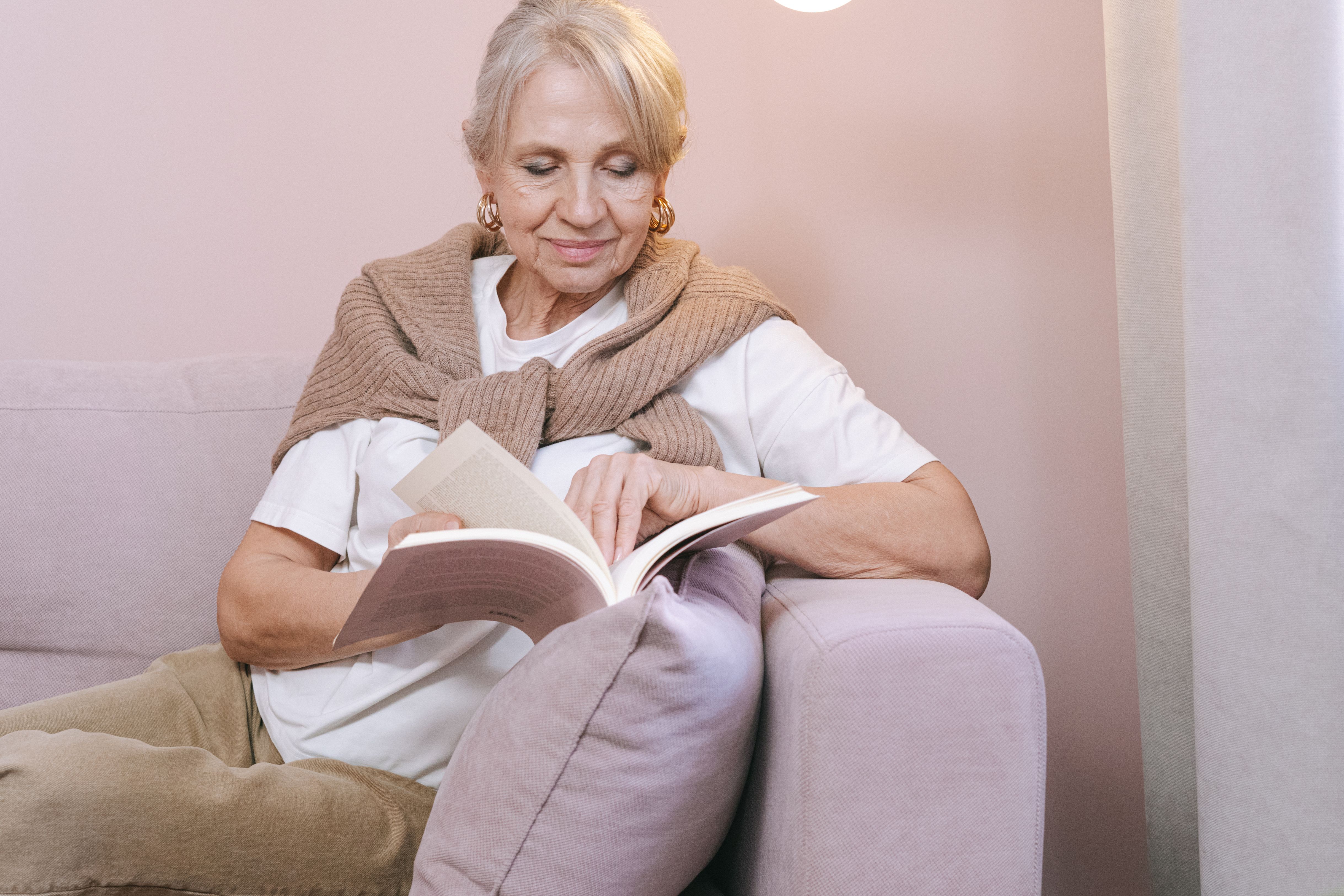 Senior woman with book, drinking coffee, reading