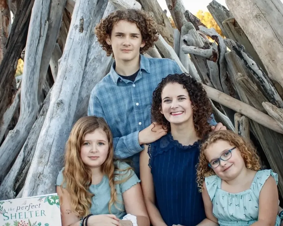 Portrait-style image of a founder (woman in her 30s) holding a picture book in a bright home library; warm natural light, bookshelves in soft focus, candid smile, portrait composition emphasizing connection; photorealistic editorial style.
