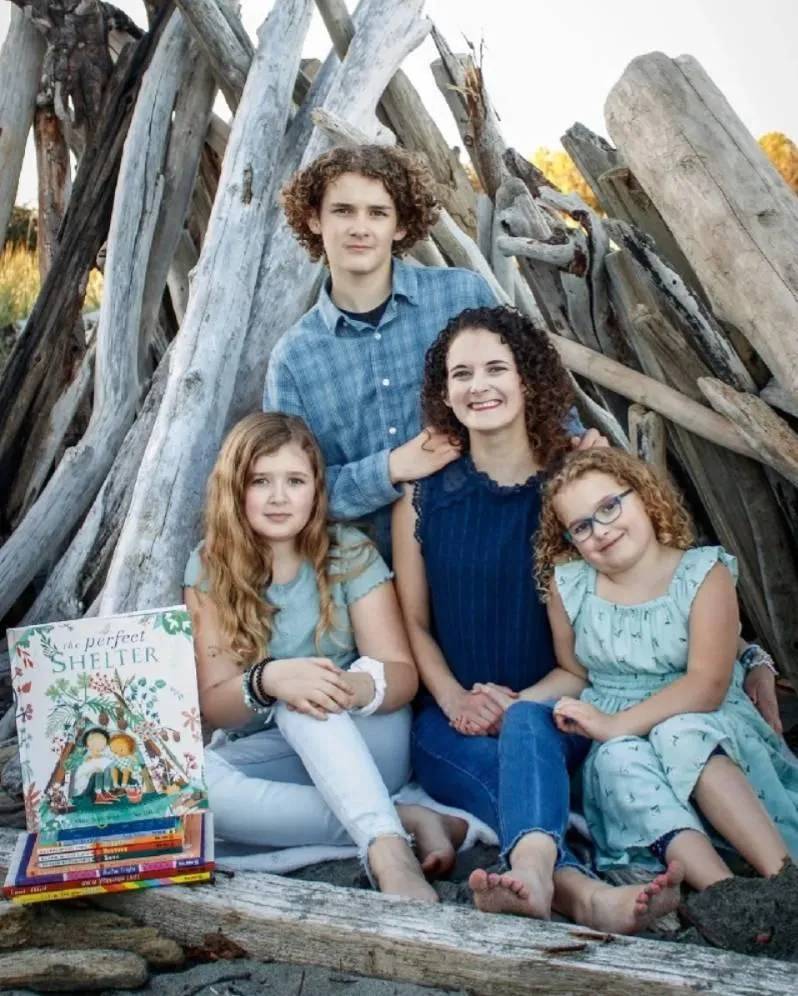 Portrait-style image of a founder (woman in her 30s) holding a picture book in a bright home library; warm natural light, bookshelves in soft focus, candid smile, portrait composition emphasizing connection; photorealistic editorial style.