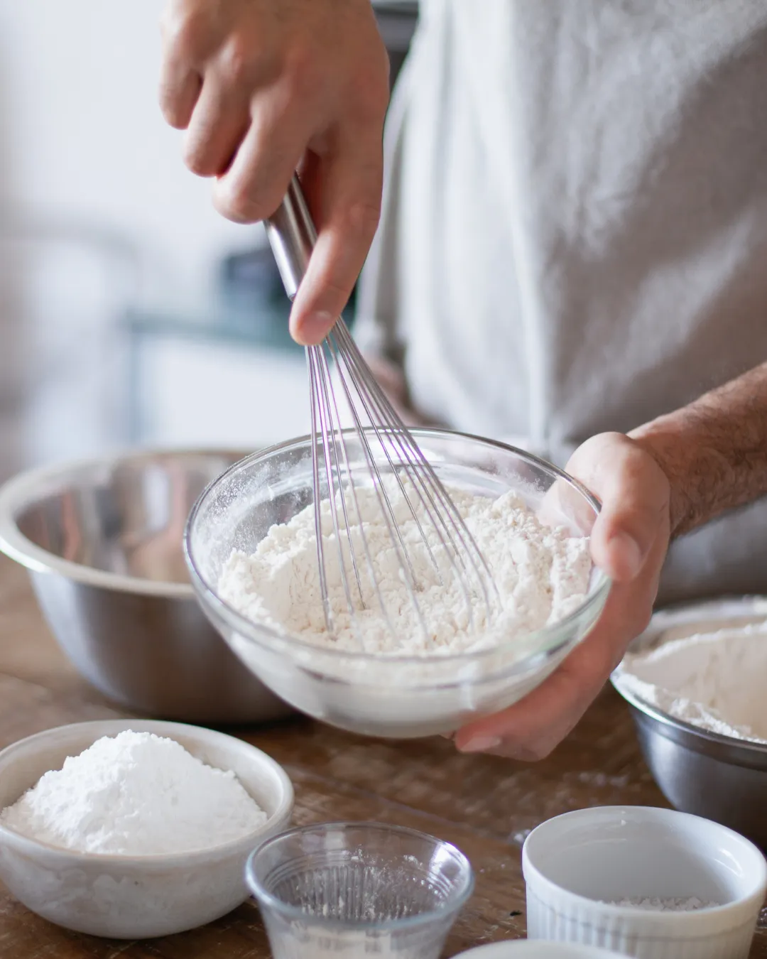 baker's hand with a whisk ina bowl of dough