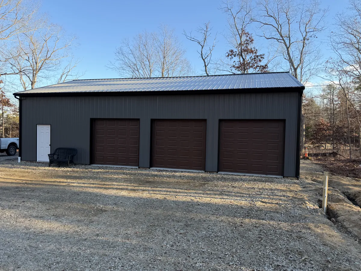 Gray three-bay pole garage with brown overhead doors