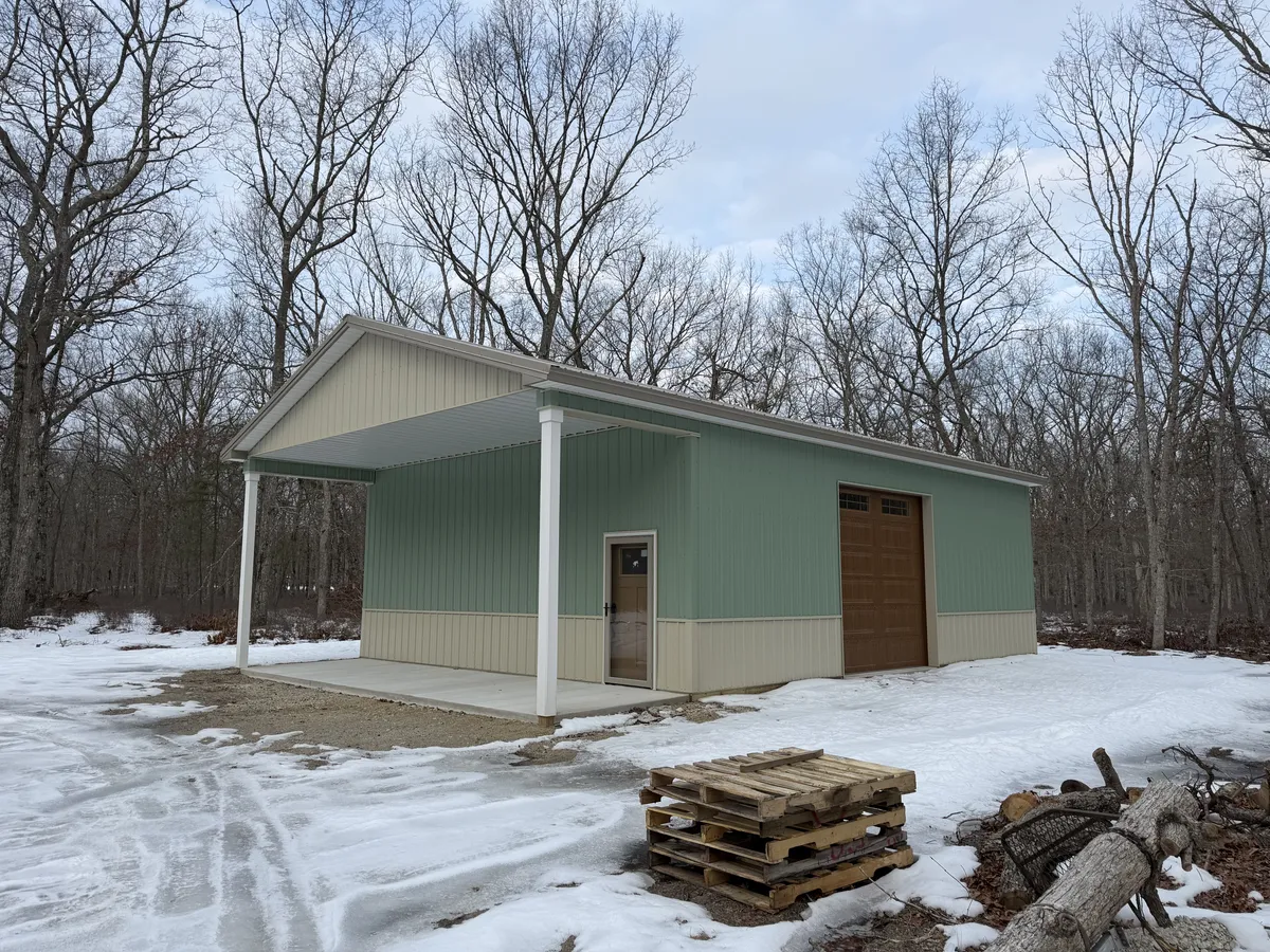 Finished green Cimino post-frame building with covered porch and overhead door