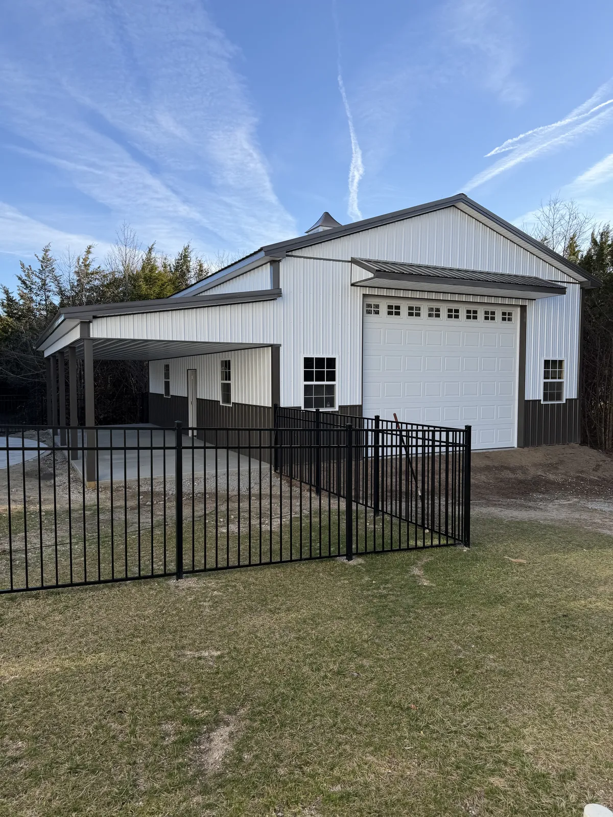Completed white Cimino garage with tall overhead door and fenced lawn