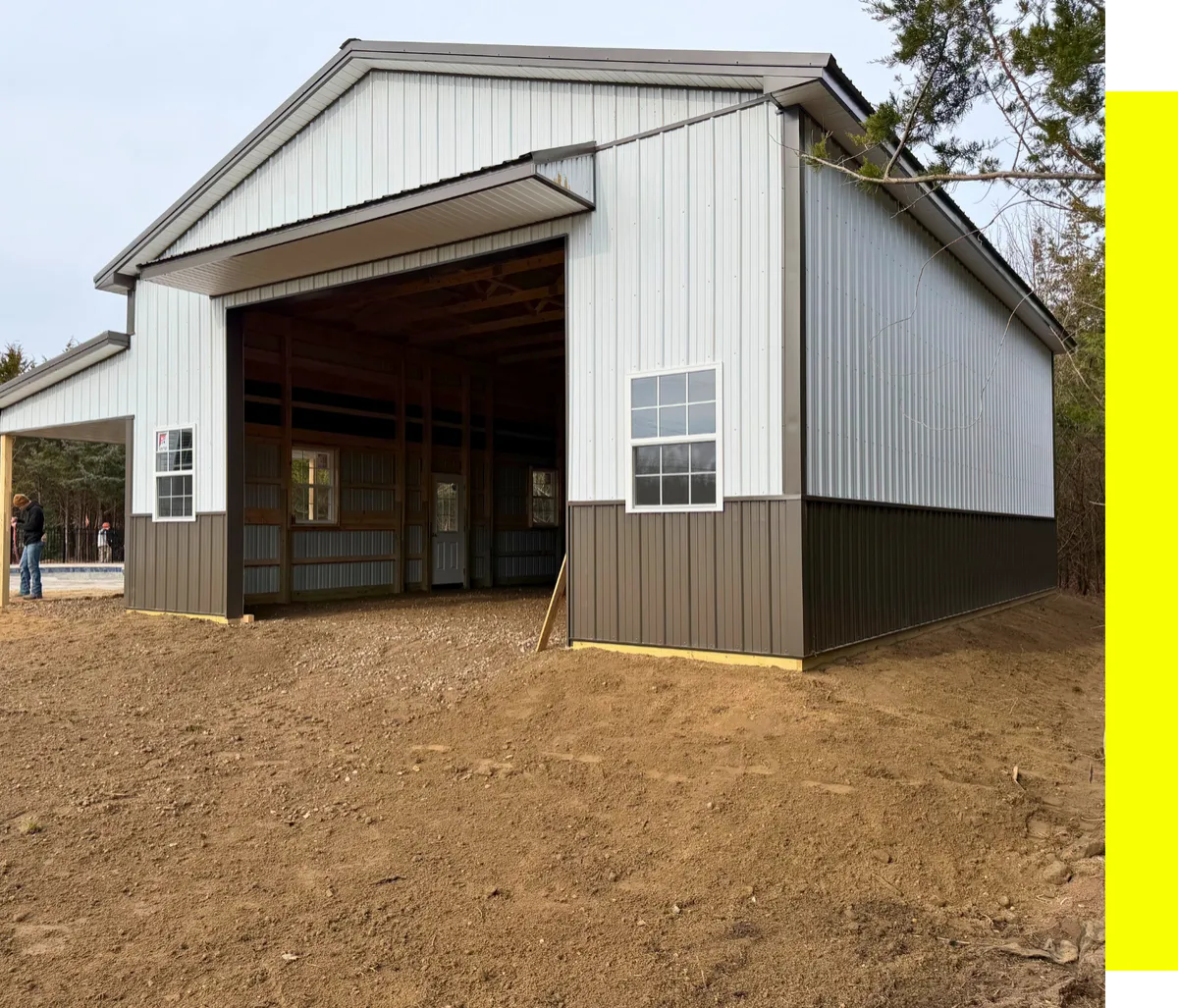 White pole building under construction with an open overhead doorway
