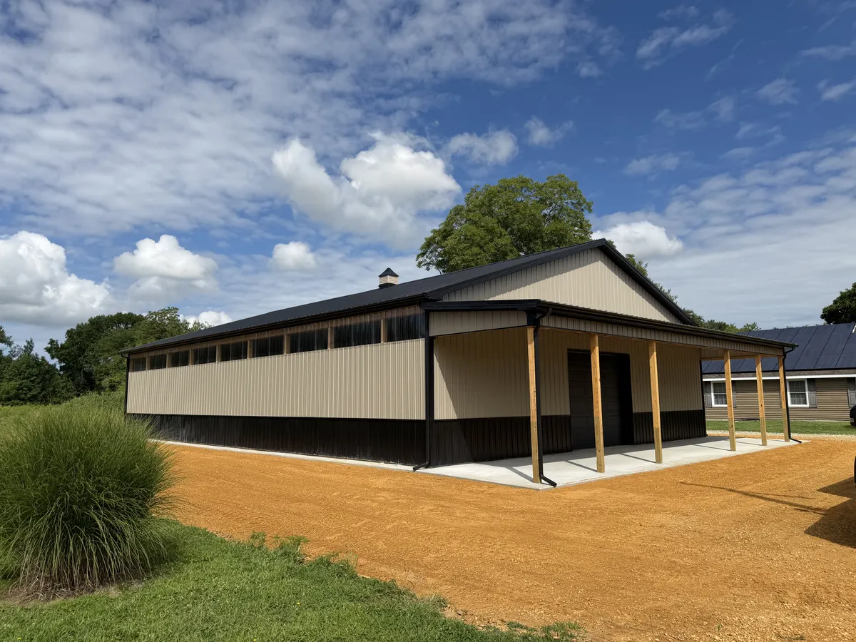 Tan pole building with high windows and a covered porch