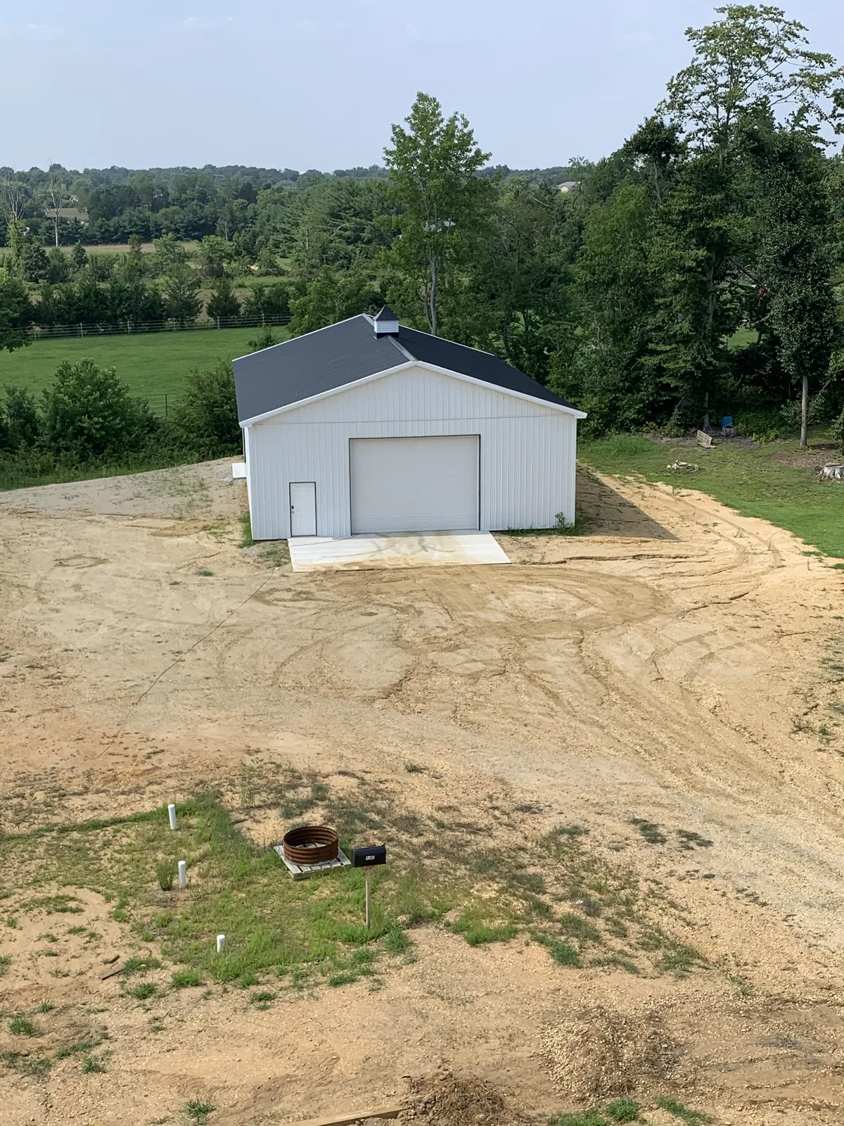 Aerial view of a white pole barn surrounded by freshly graded land