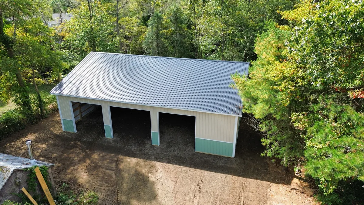 Aerial view of a cream and green three-bay storage building among trees