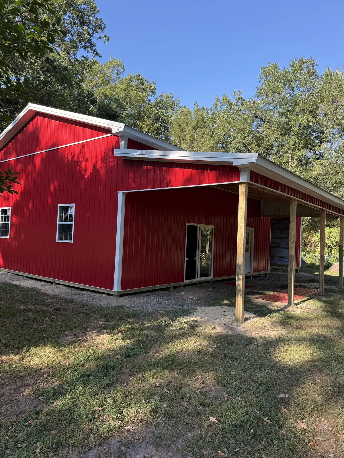 Red post-frame building with covered porch during construction