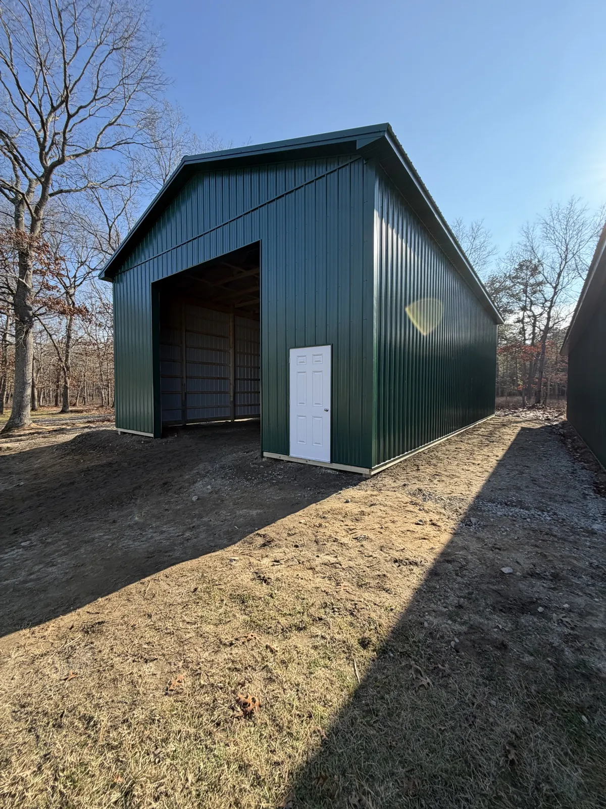 Tall green metal garage with white trim during construction