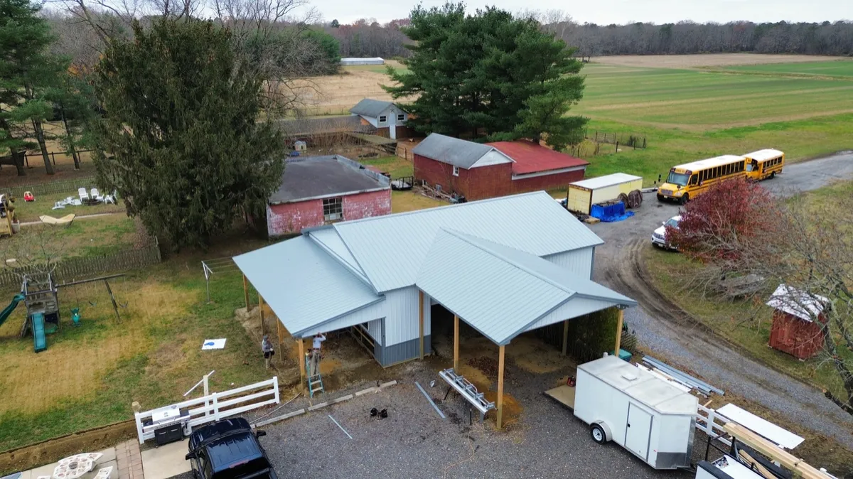Aerial view of a light-colored post-frame building with covered side areas