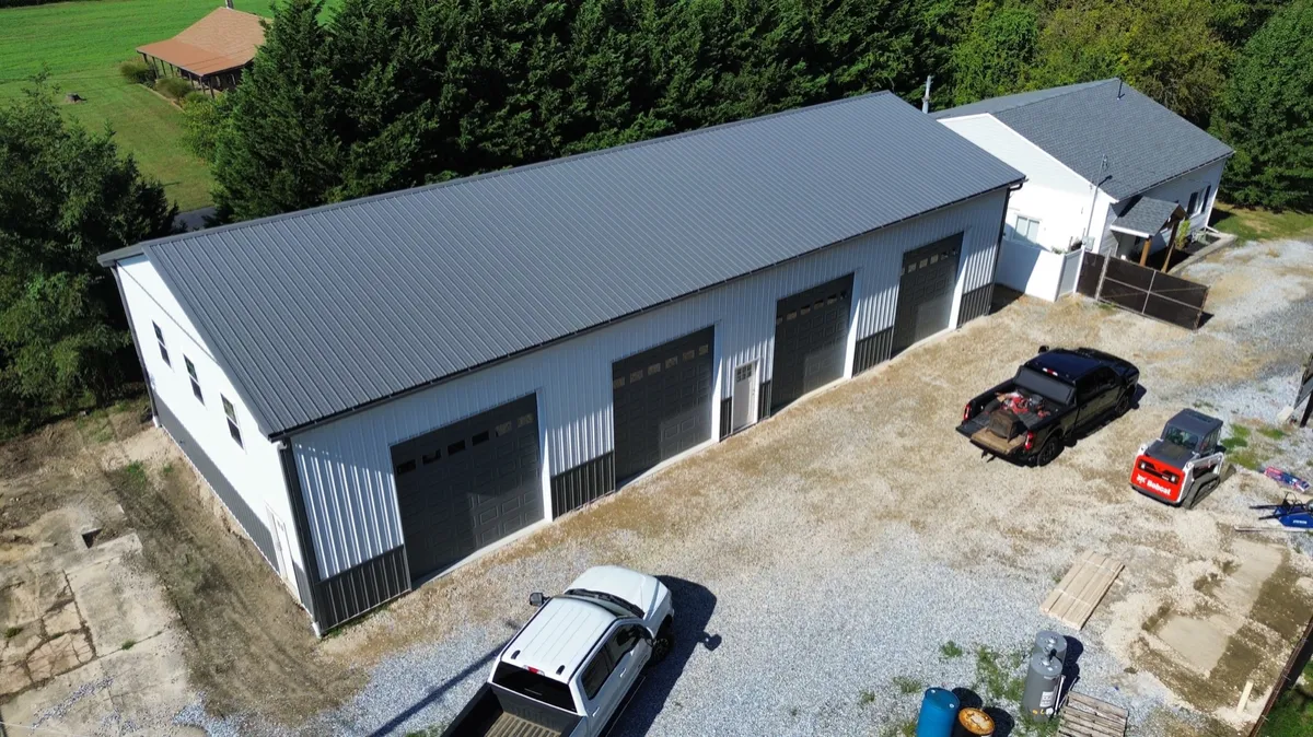 Aerial view of a white four-bay garage with black roof and concrete apron