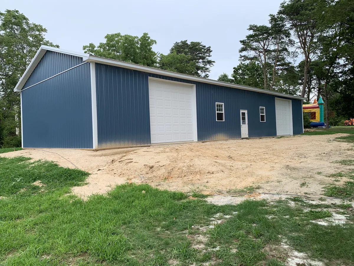 Long blue pole building with two tall white overhead doors