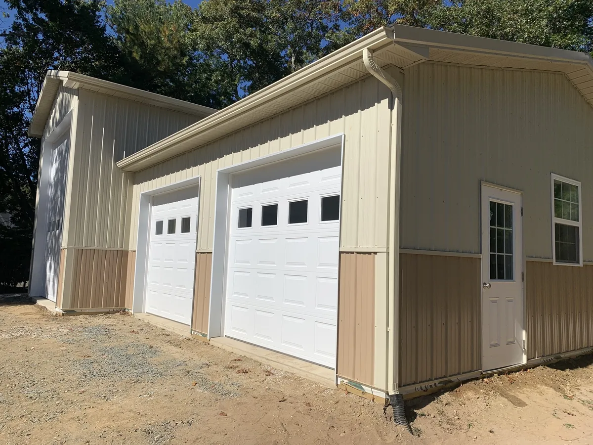 Cream pole garage with white overhead doors and contrasting wainscot