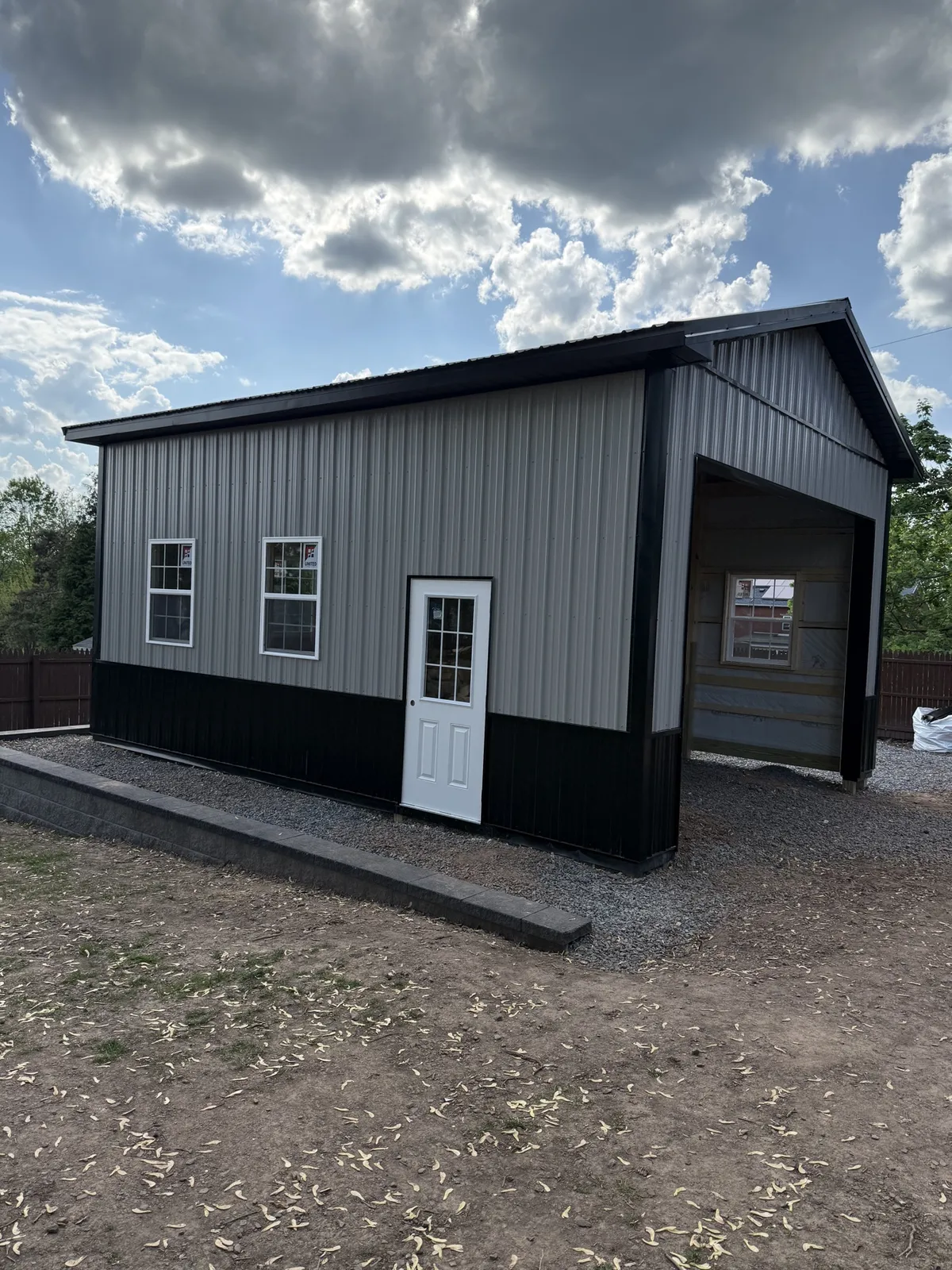 Compact gray and black post-frame workshop during construction