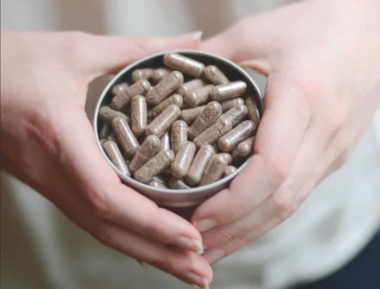 A woman holding a tin full of pills in her hands