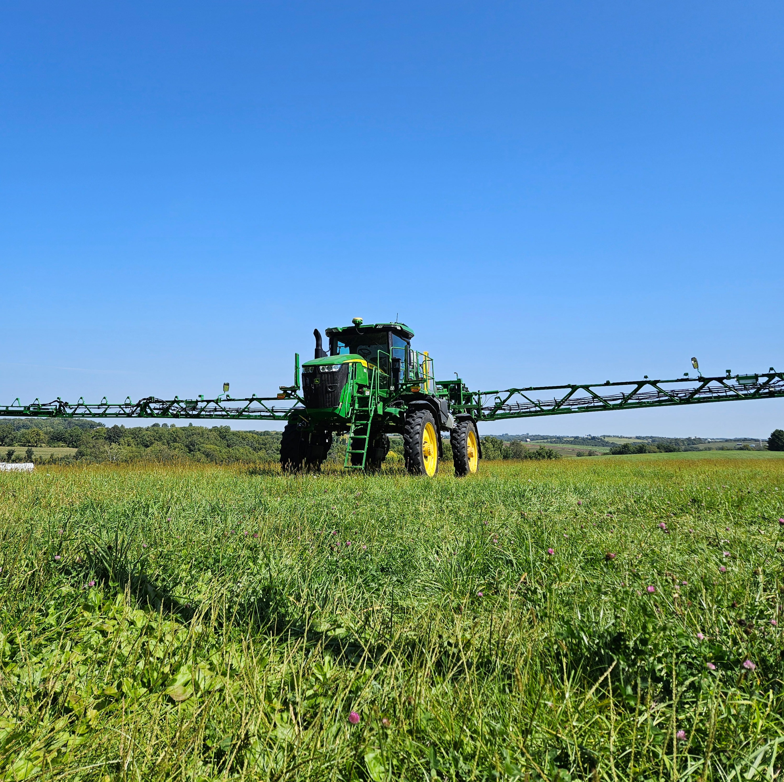Farm equipment spraying crops at sunrise for chemical crop protection and pest control