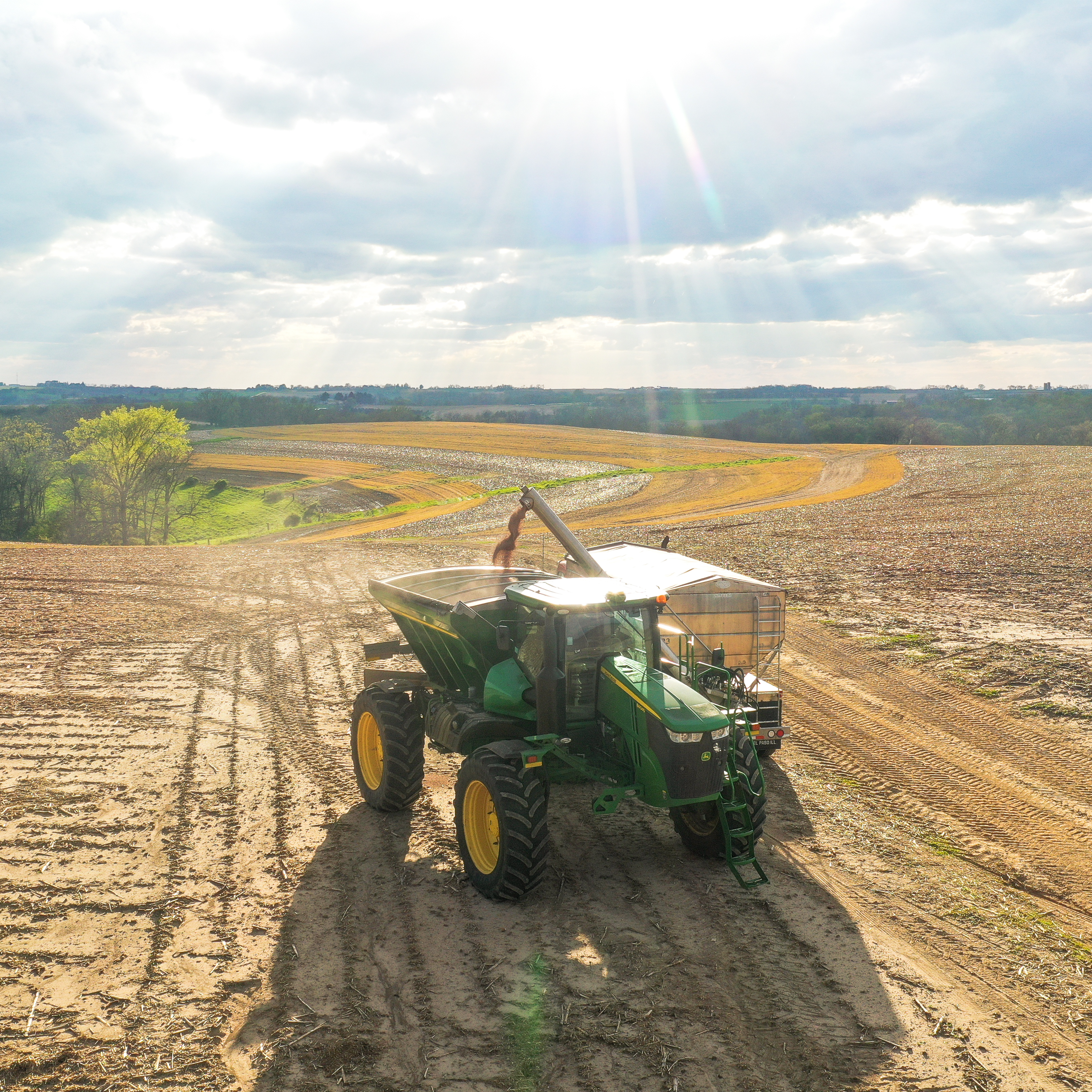 Farm fertilizer spreader applying nutrients across a green agricultural field for crop growth