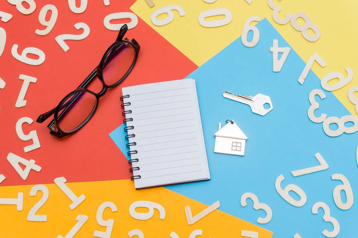 Notebook, glasses and a house key arranged for property planning