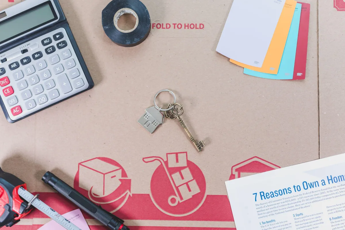 Calculator, keys and home-planning materials arranged on a desk