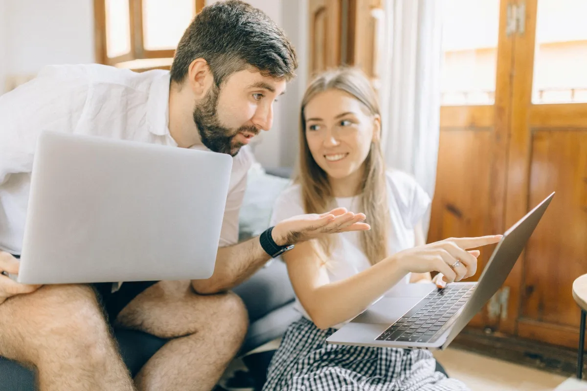 A couple comparing information together on laptops