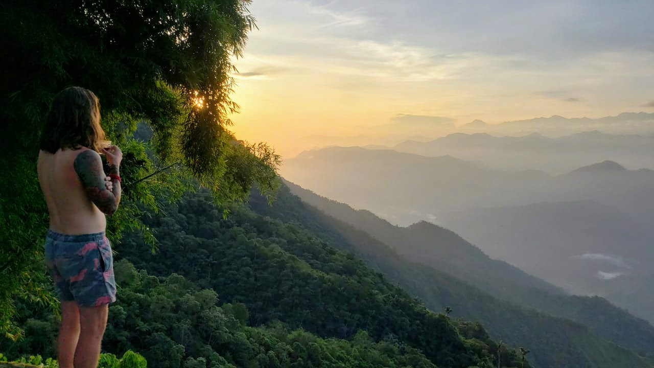 man standing on the edge of a click overlooking a valley and mountains in Colombia