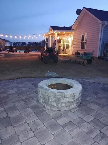 Aerial view of a completed estate landscape with terraces, illuminated pathways, and layered planting beds at golden hour.