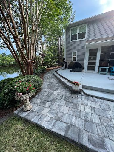 High-end lakeside patio with multi-toned bluestone pavers, integrated seating, and LED step lighting at dusk.