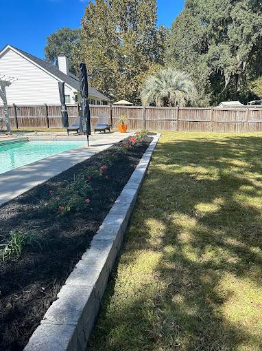 Urban courtyard with porcelain pavers, irrigation planters, boulder accents, and warm evening lighting.