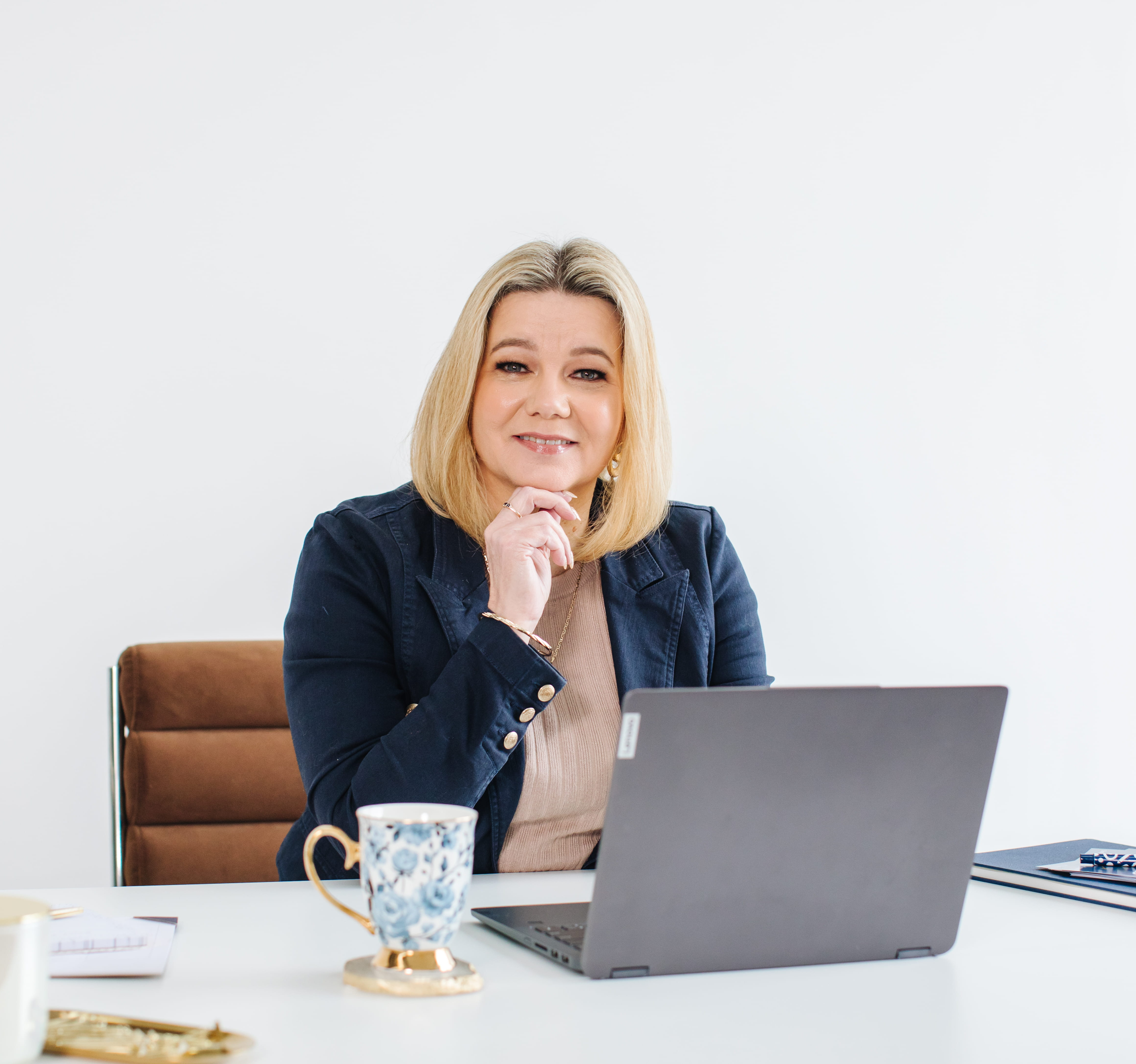 A calm, smiling author holding a notebook in a bright, natural-light setting