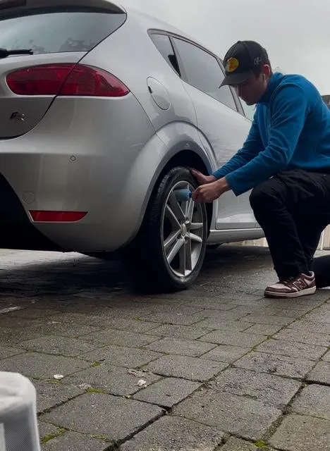 photo of andrew cleaning the wheel of a silver Seat Leon
