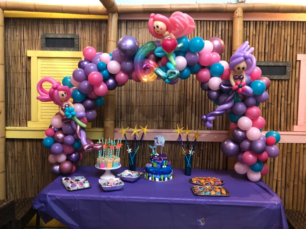 Colorful balloon arch with character theme over party table setup