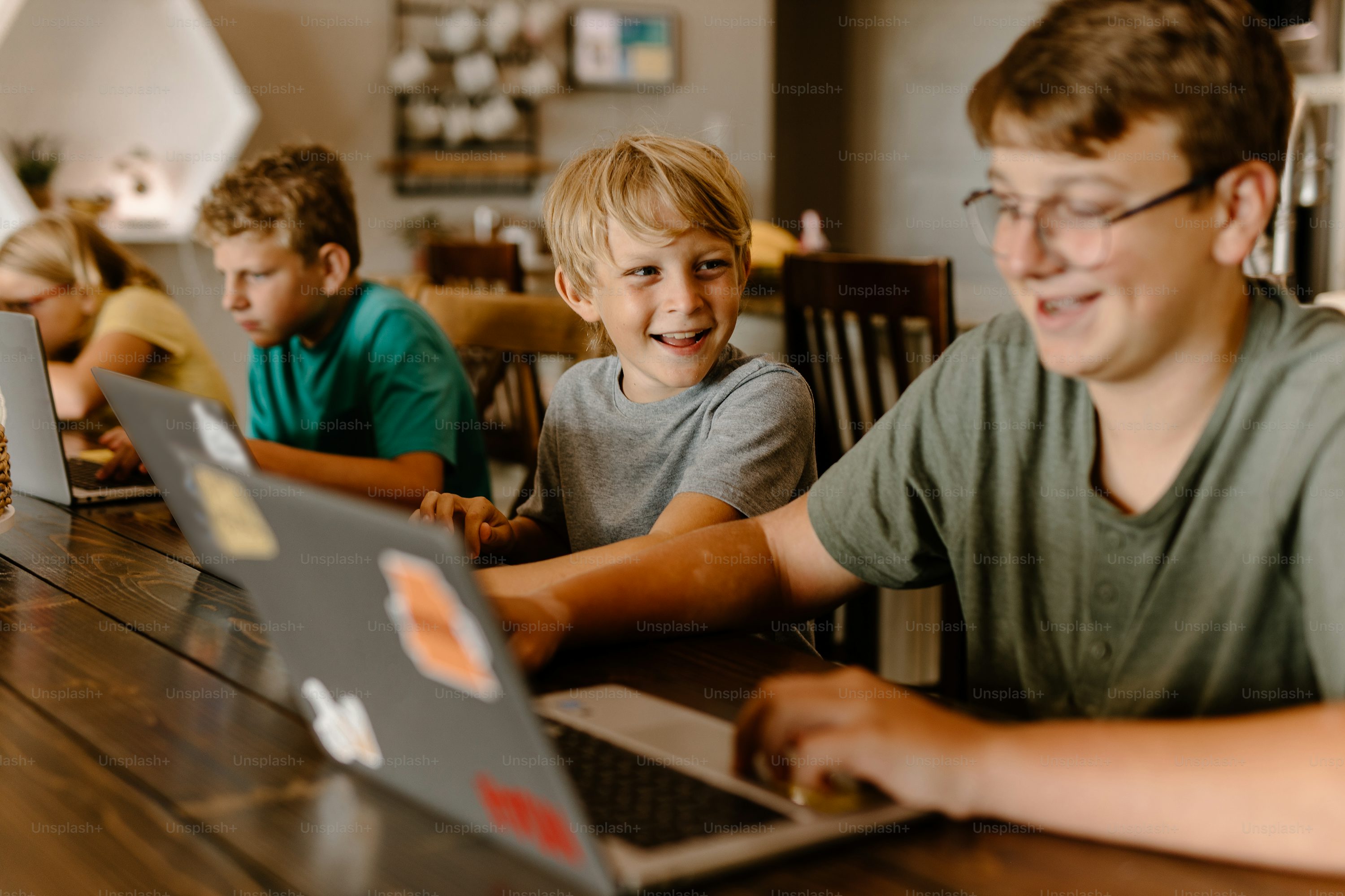 Students sit in a semicircle watching the teacher on a laptop