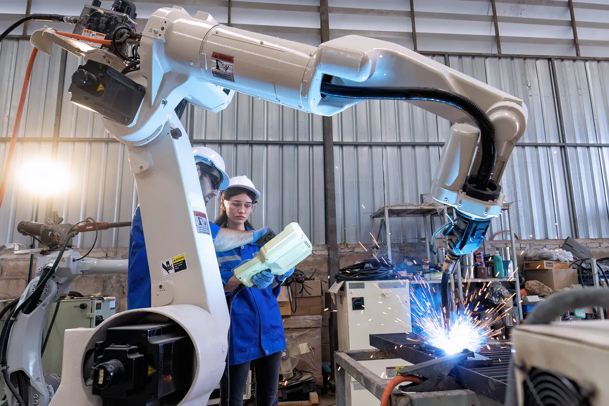 Engineers Operating Robotic Welding Arm in a Factory