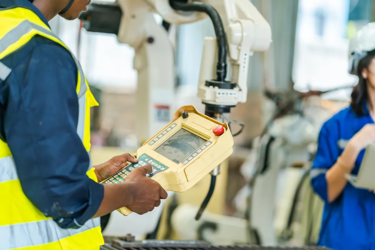 Worker controls robotic arm in modern factory setting