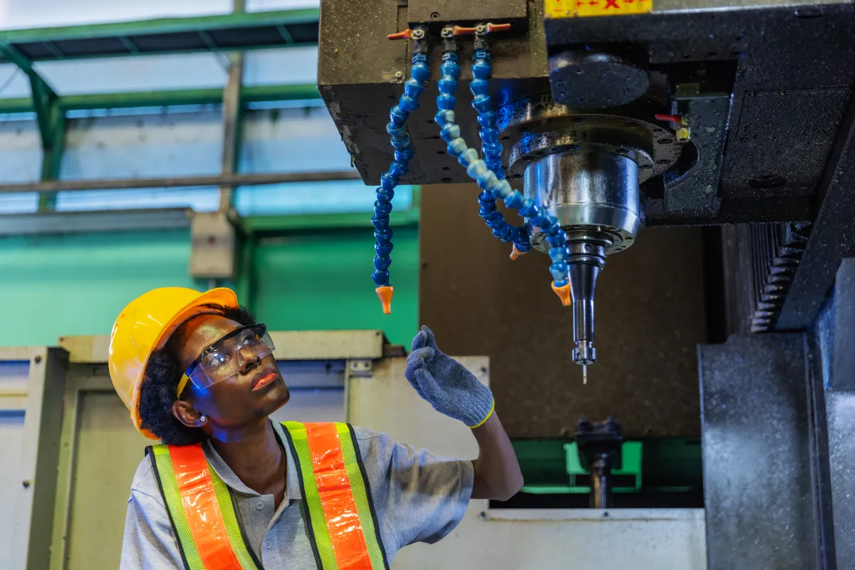 Professional female industrial worker inspecting large machinery in factory