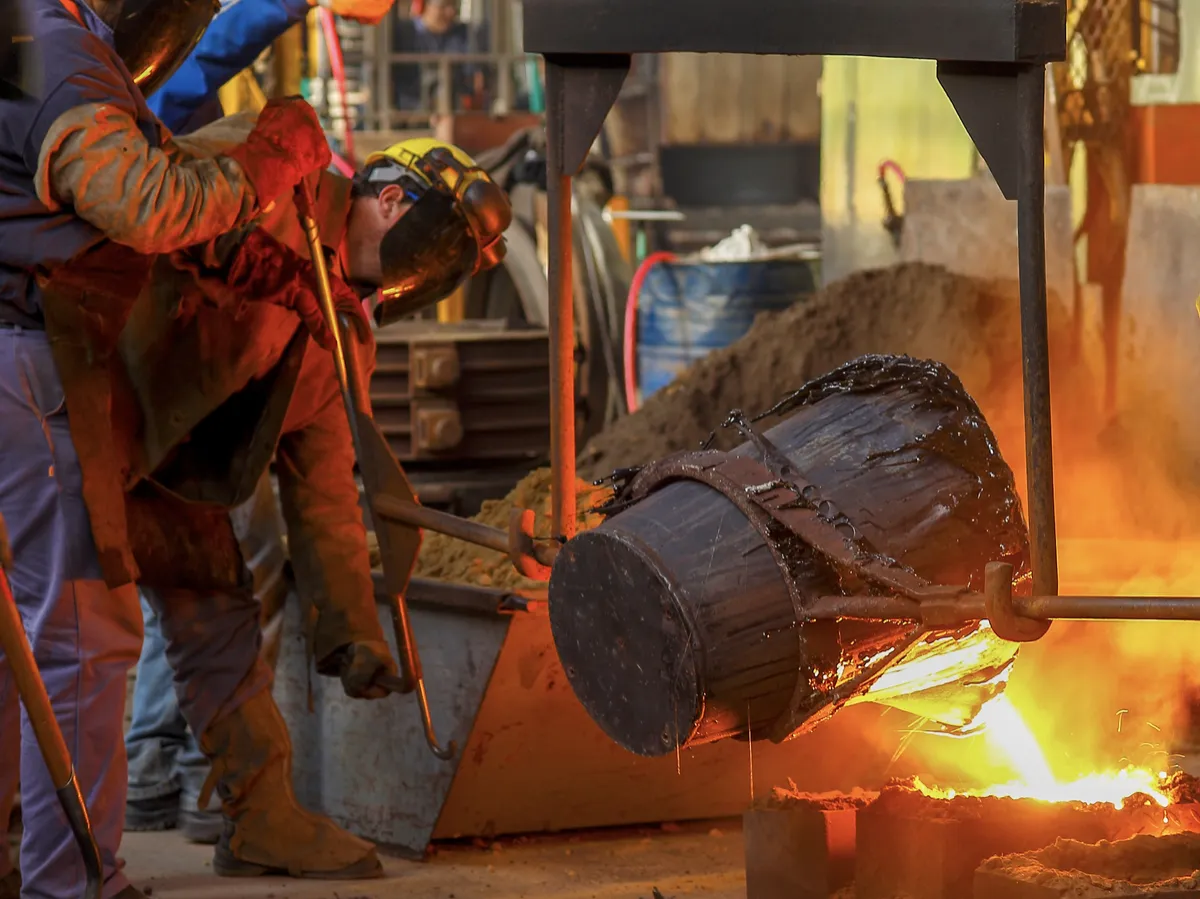 Industrial workers pouring molten metal in a factory
