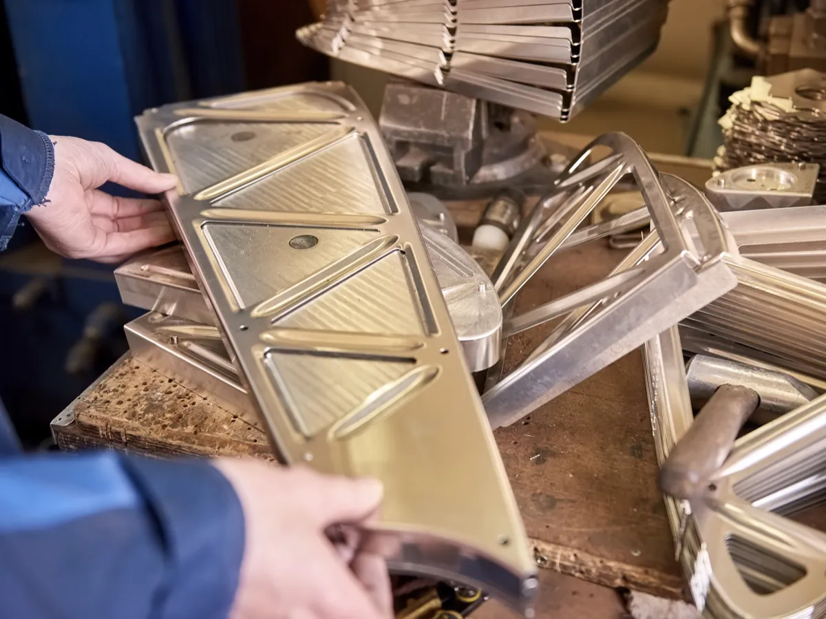 Worker inspecting newly manufactured metal component in a factory setting
