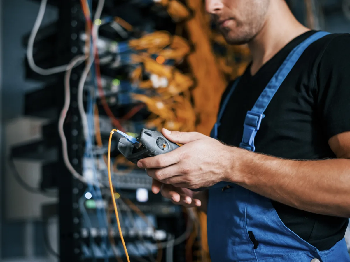 Technician inspecting fiber optic cables at server room