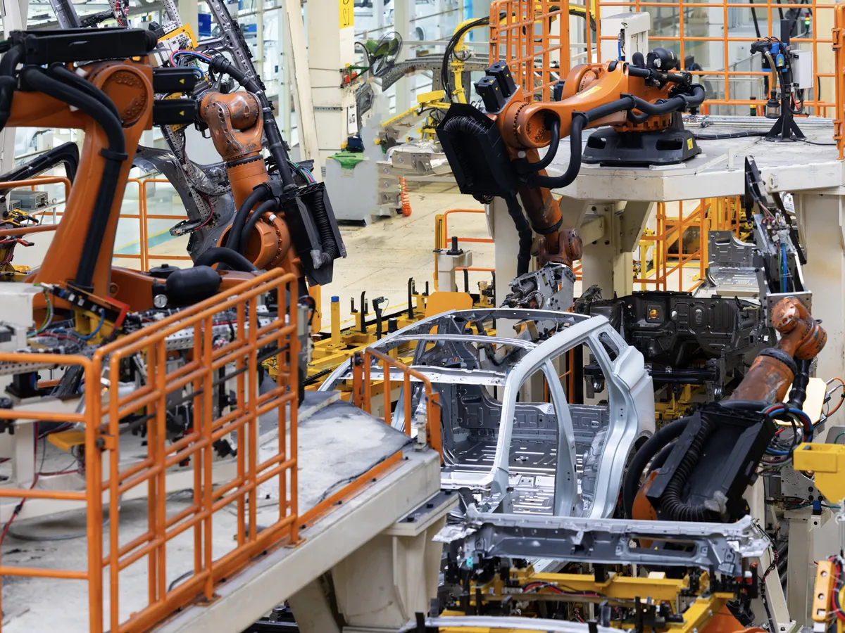 Automated robots assembling car frames in a factory
