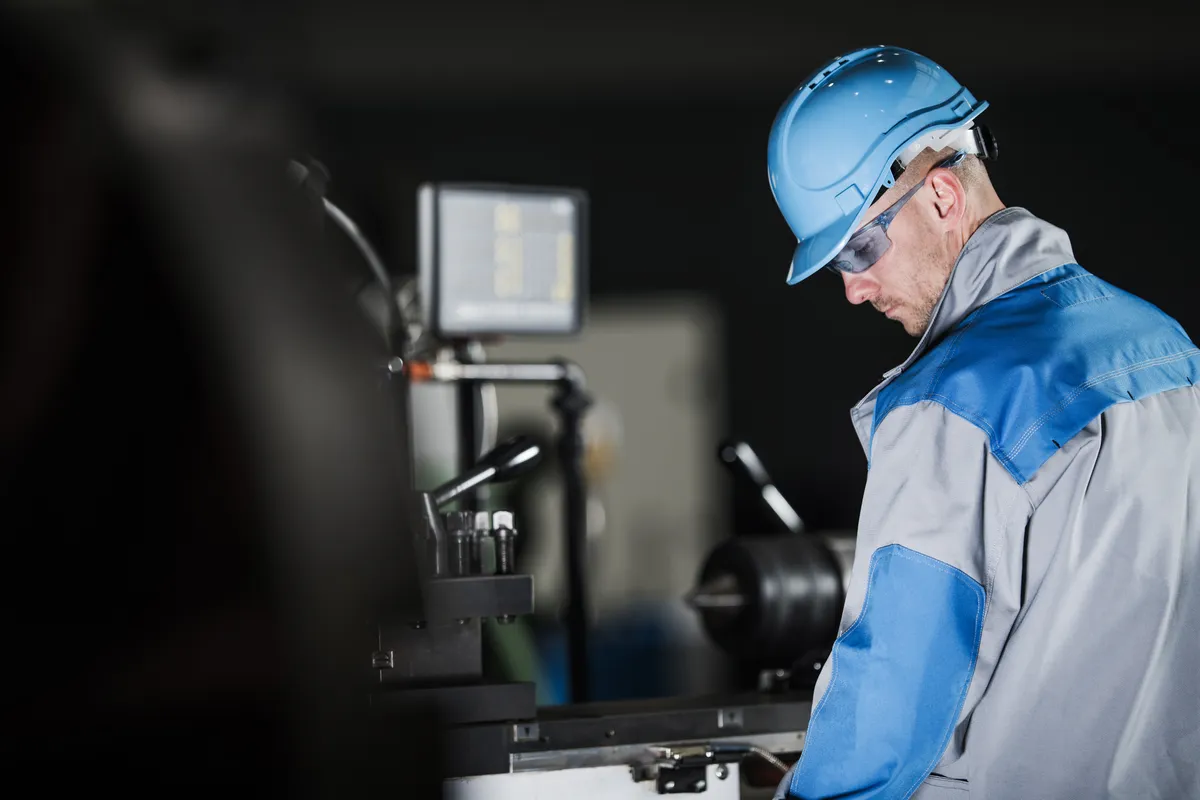 Man in safety helmet working on machinery