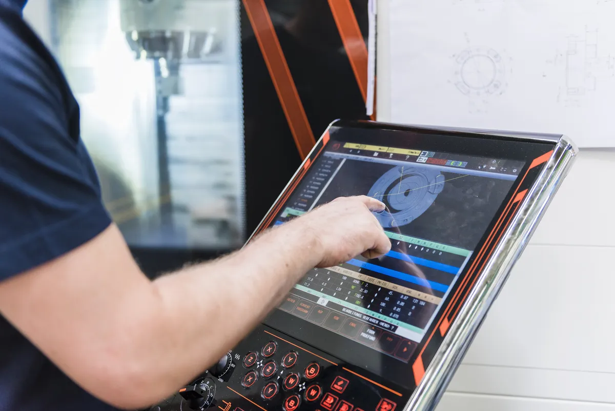 Man using a touchscreen control panel in a factory setting